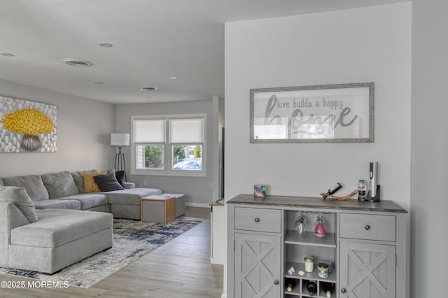 living area with wood finished floors, visible vents, and baseboards