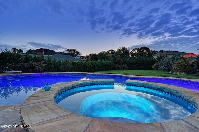 view of pool with a lawn and a pool with connected hot tub