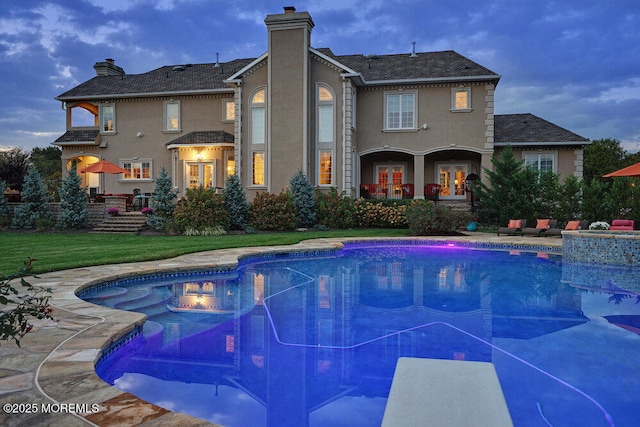 outdoor pool with a patio, a yard, french doors, and a diving board