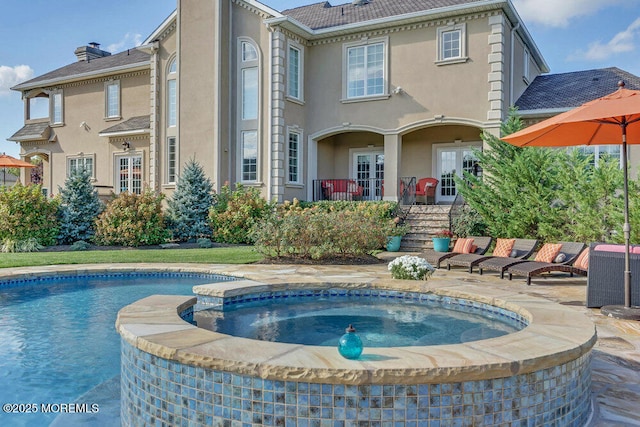 rear view of property featuring a patio area, a chimney, a pool with connected hot tub, and stucco siding