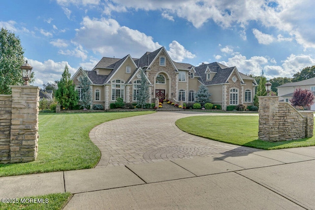 french country style house featuring stone siding, curved driveway, and a front lawn