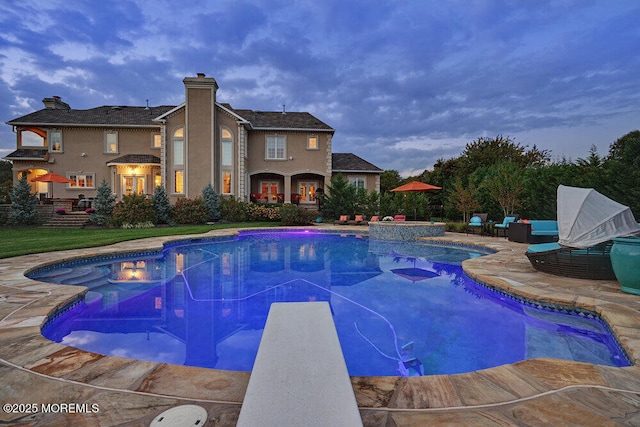 pool with a patio area and a diving board