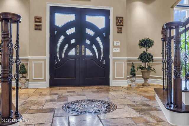 entryway featuring french doors, baseboards, and stone tile flooring