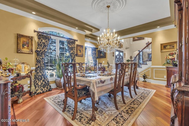 dining room featuring hardwood / wood-style floors, crown molding, stairway, and wainscoting