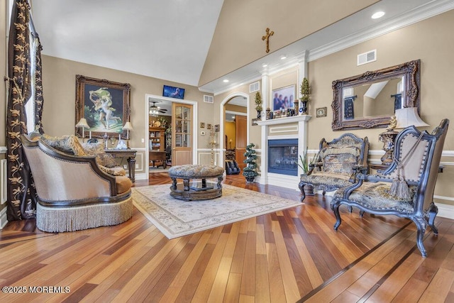 living room featuring visible vents, wood-type flooring, a fireplace, and crown molding