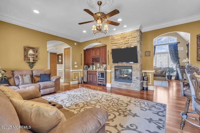 living area featuring wine cooler, a fireplace, crown molding, and light wood finished floors