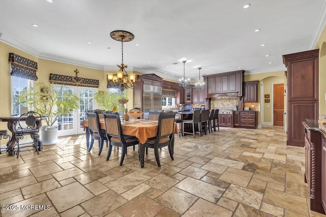 dining area with an inviting chandelier, stone tile floors, arched walkways, and a wealth of natural light