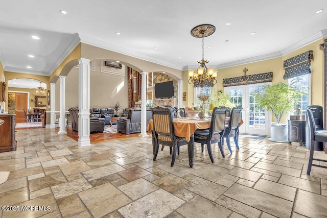 dining room featuring ornate columns, an inviting chandelier, recessed lighting, arched walkways, and stone tile flooring