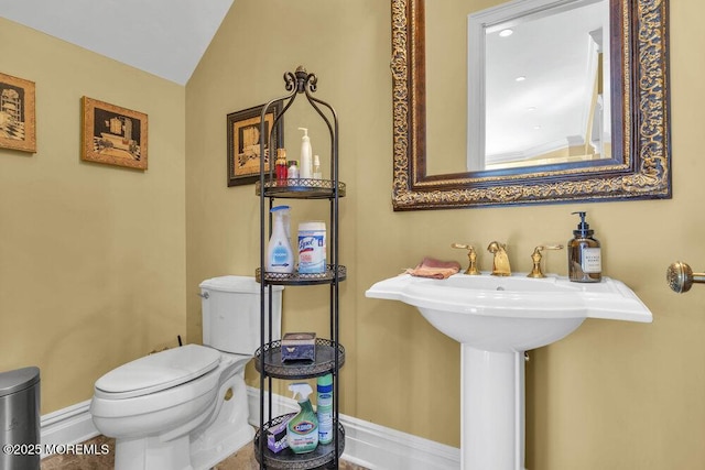 bathroom with baseboards, toilet, and vaulted ceiling