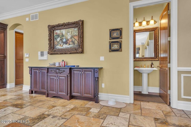 hall featuring visible vents, baseboards, arched walkways, and stone tile floors