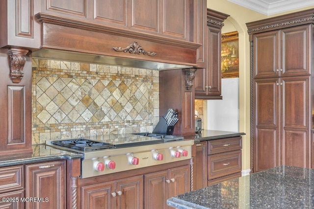 kitchen featuring ornamental molding, tasteful backsplash, dark stone counters, custom exhaust hood, and stainless steel gas cooktop