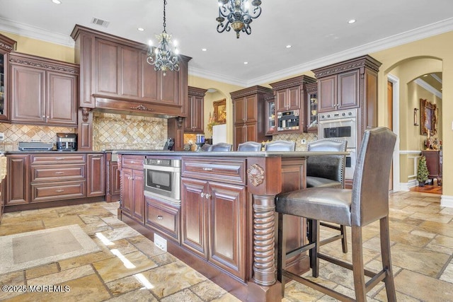 kitchen featuring stone tile flooring, visible vents, arched walkways, and dark countertops