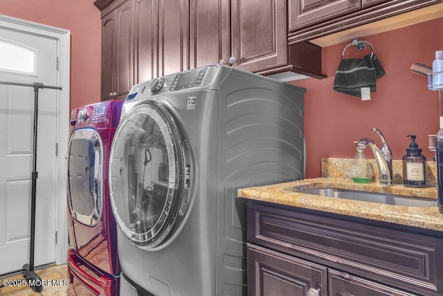 clothes washing area featuring washer and clothes dryer, cabinet space, and a sink