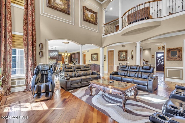 living room with hardwood / wood-style flooring, arched walkways, ornate columns, and a chandelier