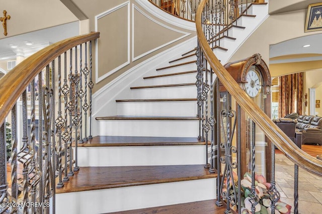 staircase featuring stone tile floors and a high ceiling