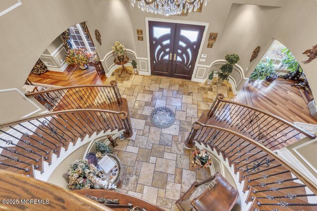 foyer entrance with visible vents, stone finish flooring, a chandelier, stairs, and french doors