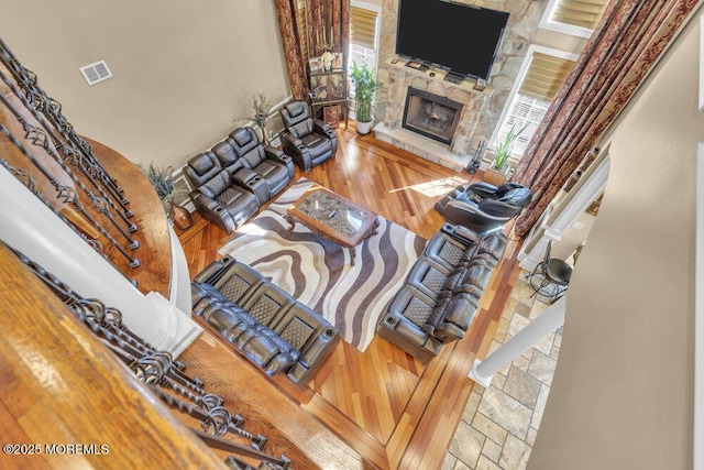 living area with a stone fireplace, wood finished floors, and visible vents