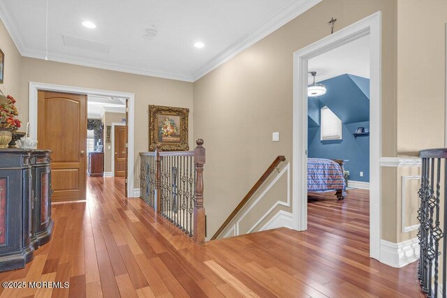 hall featuring an upstairs landing, light wood-style flooring, and crown molding