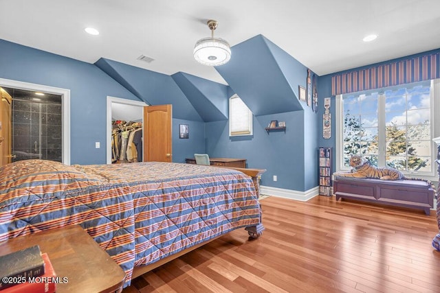 bedroom with a spacious closet, multiple windows, wood finished floors, and visible vents