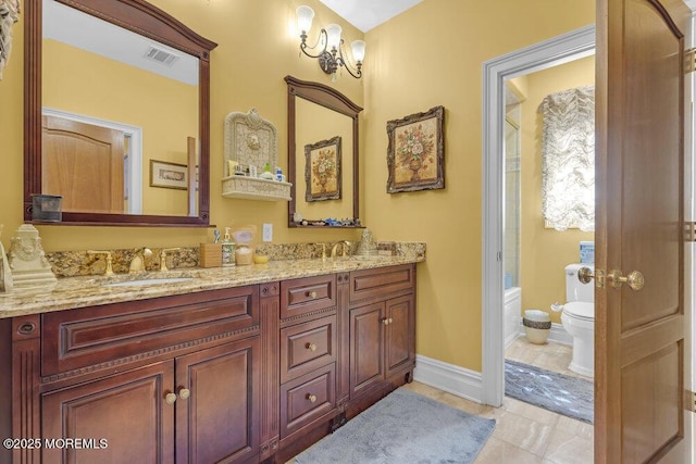 bathroom with visible vents, baseboards, toilet, double vanity, and a sink