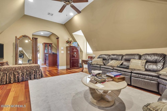 living room featuring a ceiling fan, wood finished floors, visible vents, lofted ceiling, and arched walkways