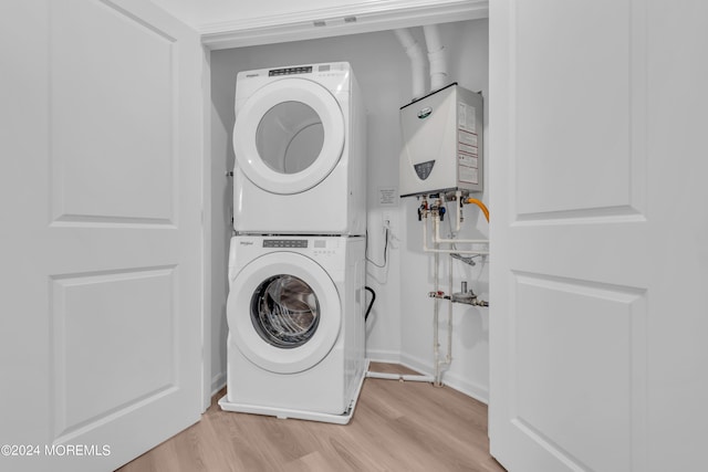 clothes washing area featuring laundry area, water heater, light wood-style floors, and stacked washer and clothes dryer