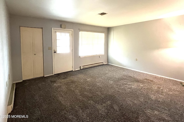 spare room featuring dark colored carpet, baseboards, visible vents, and baseboard heating