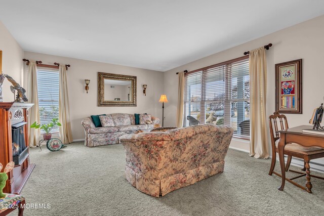 living area featuring carpet floors, baseboards, and a glass covered fireplace