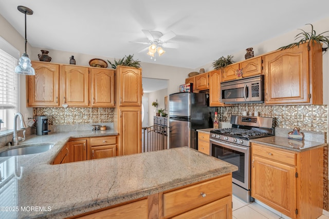 kitchen featuring appliances with stainless steel finishes, a sink, light stone counters, and decorative backsplash