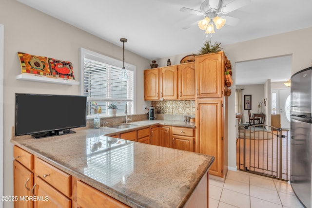 kitchen with plenty of natural light, freestanding refrigerator, a sink, and light tile patterned floors