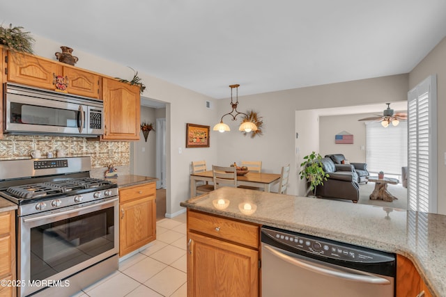 kitchen featuring stainless steel appliances, hanging light fixtures, backsplash, open floor plan, and light tile patterned flooring