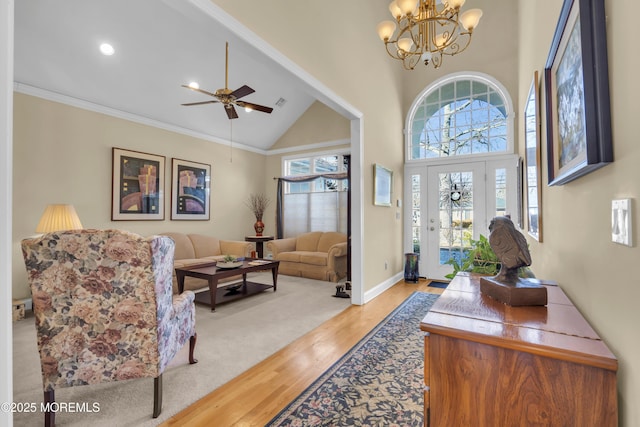 interior space featuring crown molding, wood finished floors, high vaulted ceiling, baseboards, and ceiling fan with notable chandelier