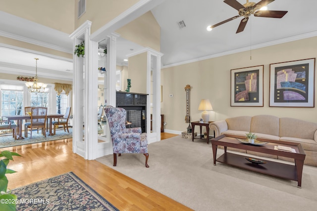 living room with visible vents, ornamental molding, wood finished floors, a multi sided fireplace, and ceiling fan with notable chandelier