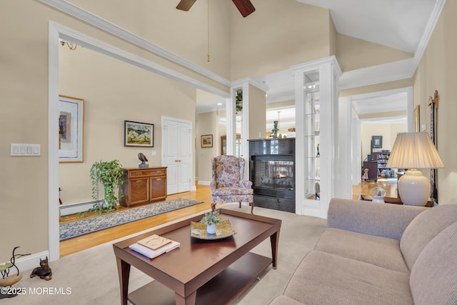 carpeted living room featuring high vaulted ceiling, baseboard heating, a multi sided fireplace, and crown molding