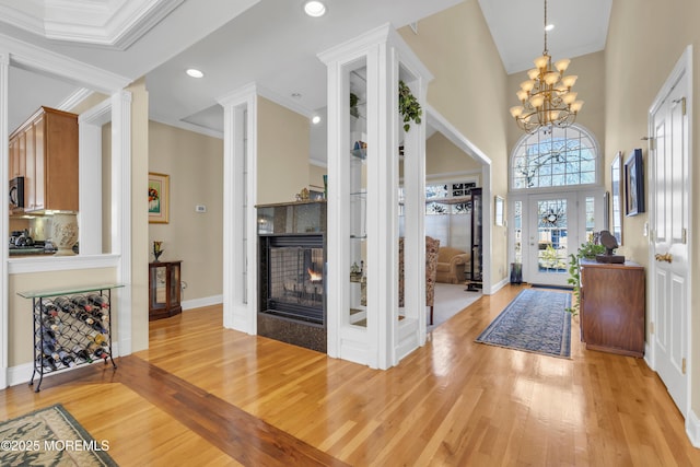 entryway with light wood finished floors, baseboards, ornamental molding, a multi sided fireplace, and recessed lighting