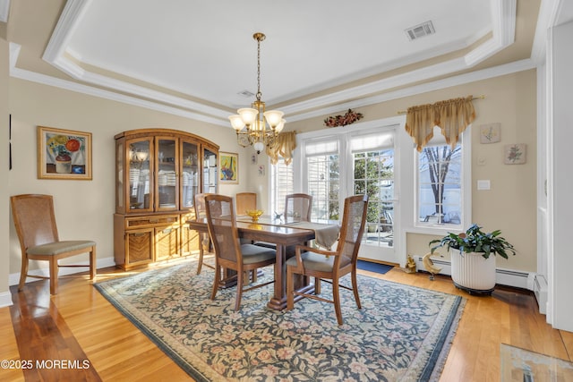 dining room with light wood-style floors, a raised ceiling, visible vents, and ornamental molding