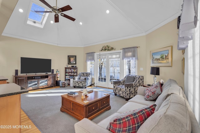 living room with high vaulted ceiling, a skylight, wood finished floors, a ceiling fan, and ornamental molding