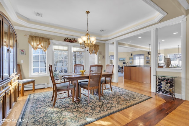 dining room with a raised ceiling, visible vents, plenty of natural light, and light wood finished floors