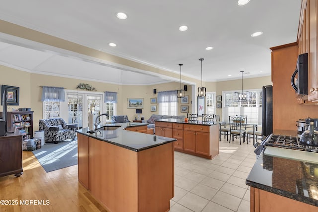 kitchen featuring open floor plan, black appliances, a sink, and a center island with sink