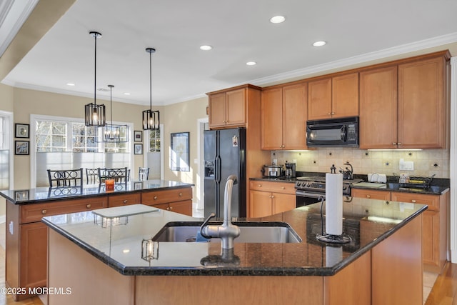 kitchen featuring a sink, ornamental molding, brown cabinets, black appliances, and an island with sink