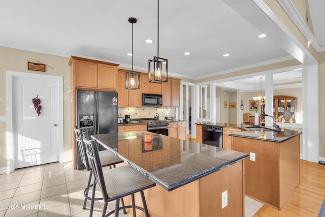 kitchen with a kitchen bar, decorative backsplash, a kitchen island with sink, a sink, and black appliances