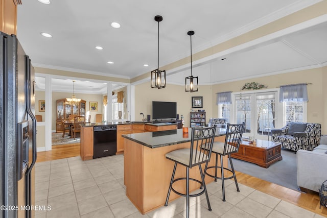 kitchen with open floor plan, black appliances, dark countertops, and a kitchen breakfast bar