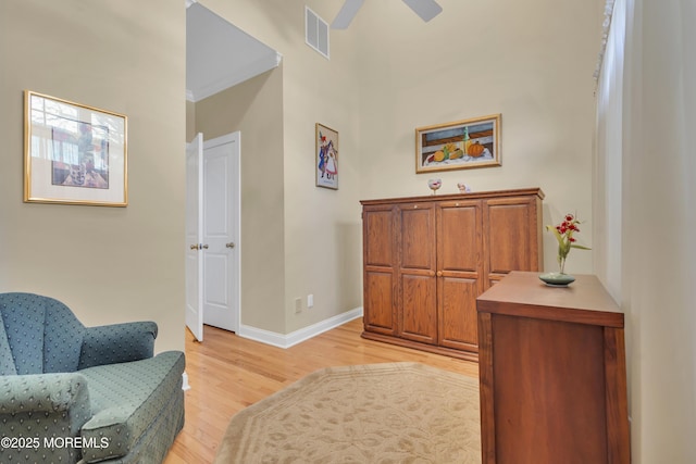 sitting room with a ceiling fan, visible vents, light wood-style flooring, and baseboards