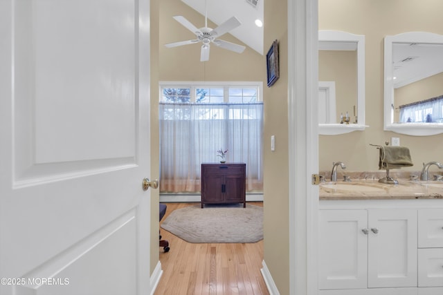 bathroom with ceiling fan, vaulted ceiling, baseboard heating, and wood finished floors