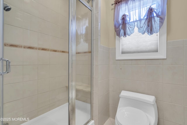 full bathroom with toilet, a shower stall, and tile walls