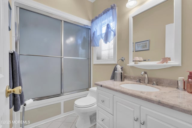 bathroom featuring enclosed tub / shower combo, vanity, toilet, and tile patterned floors