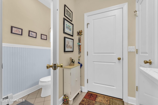 bathroom with baseboard heating, tile patterned flooring, toilet, and baseboards