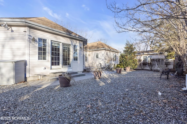 rear view of property featuring entry steps, a patio, and roof with shingles