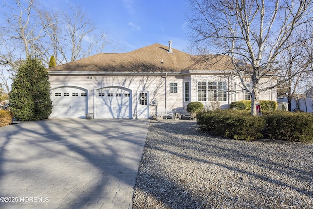 view of front of property featuring a garage, driveway, and a shingled roof