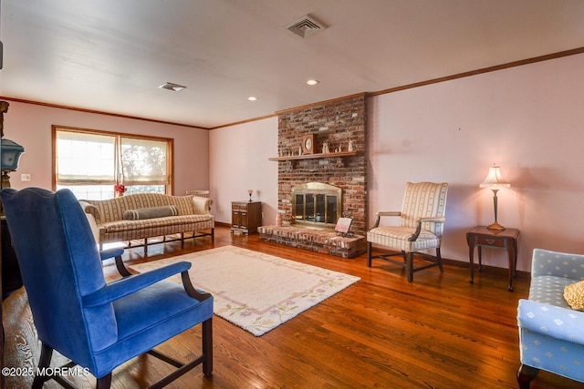 living room featuring a fireplace, wood finished floors, visible vents, and crown molding